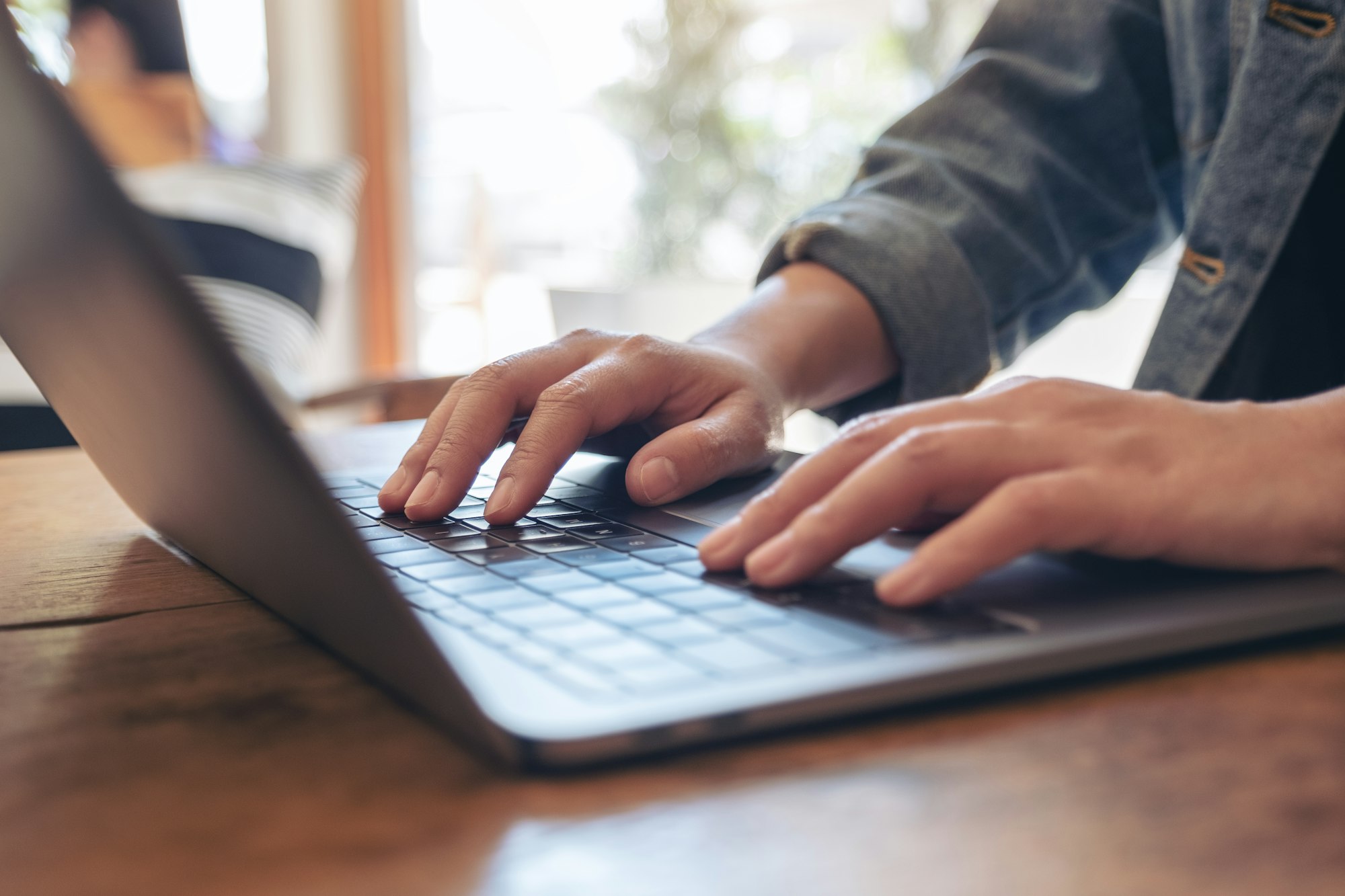 Closeup image of woman's hands using and typing on laptop keyboard on the table